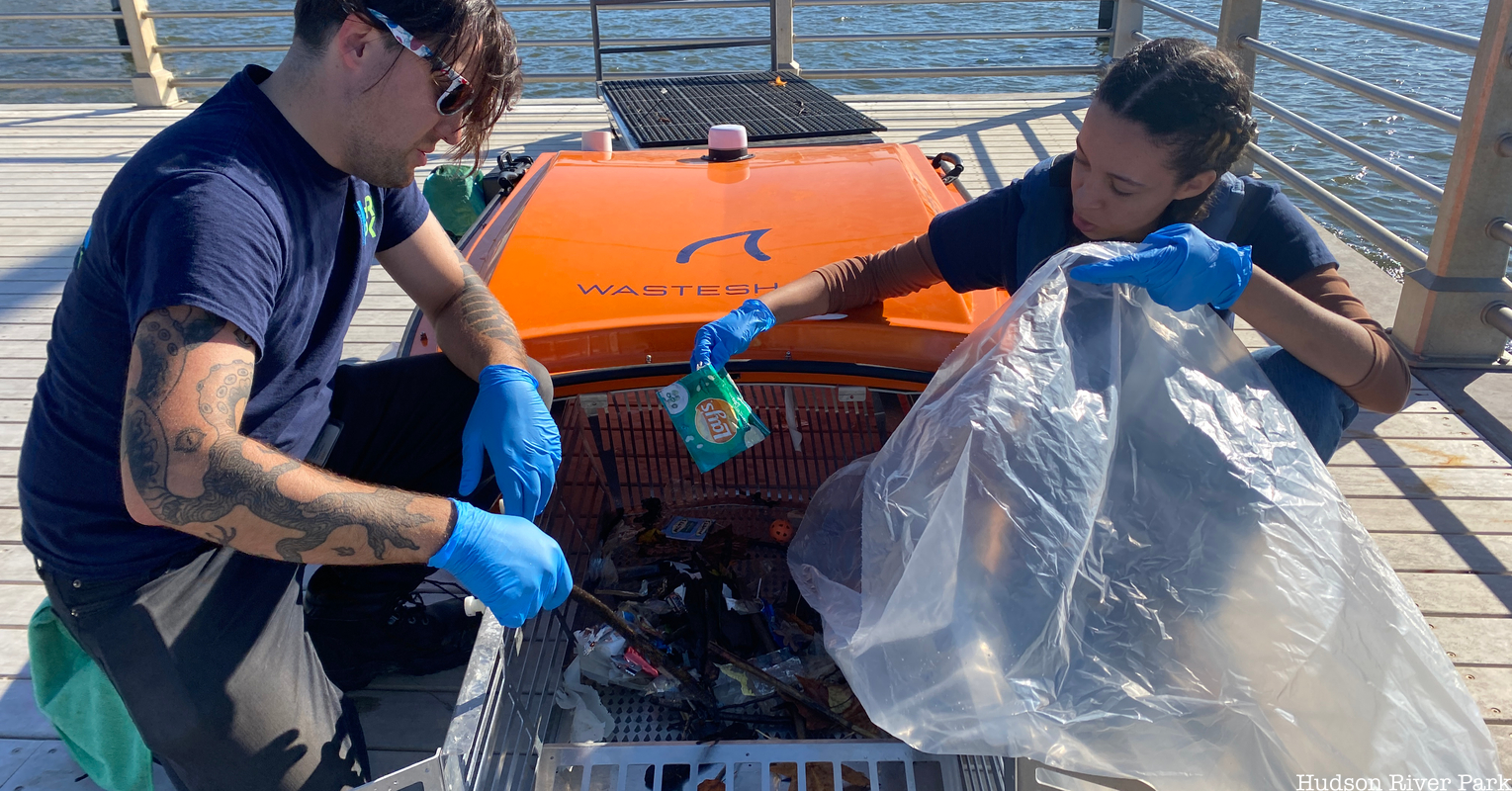 Two volunteers remove waste from the WasteShark