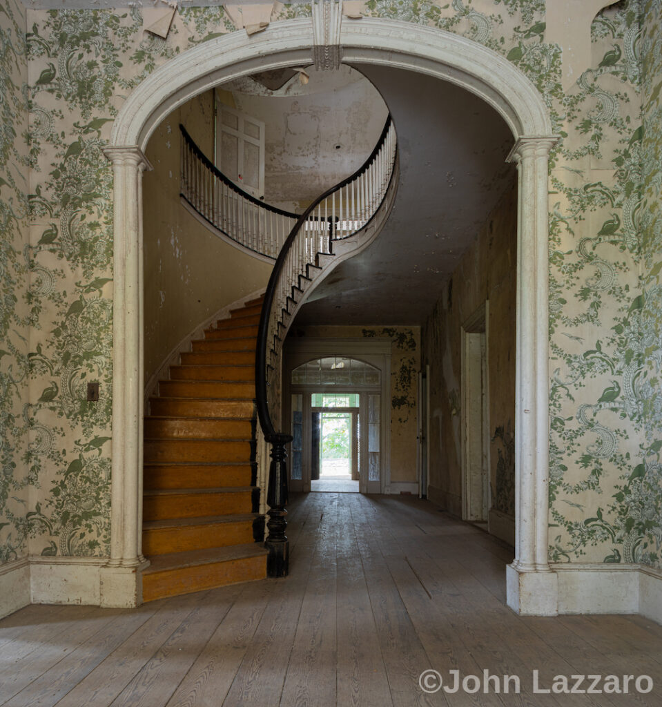 Staircase framed by an arched opening in.a wall covered in wallpaper