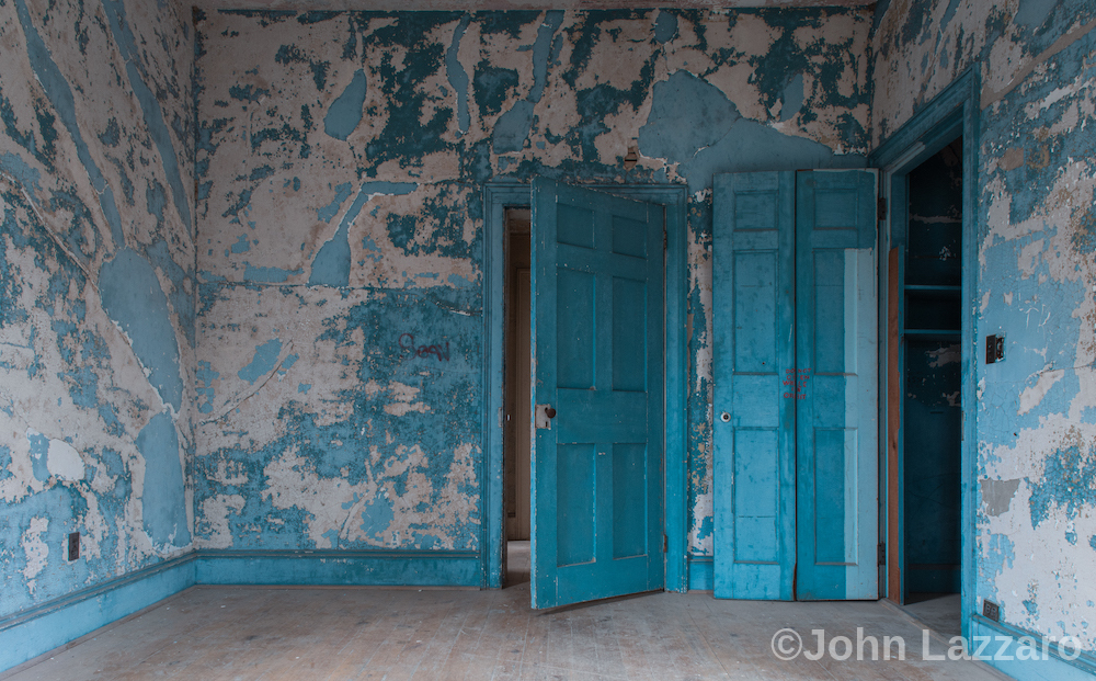 An empty room covered in bright blue paint that is peeling