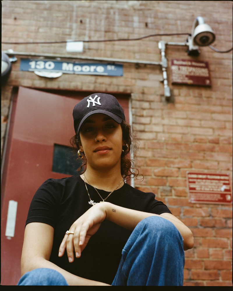 Woman in a Yankee cap sitting in front of a brick building
