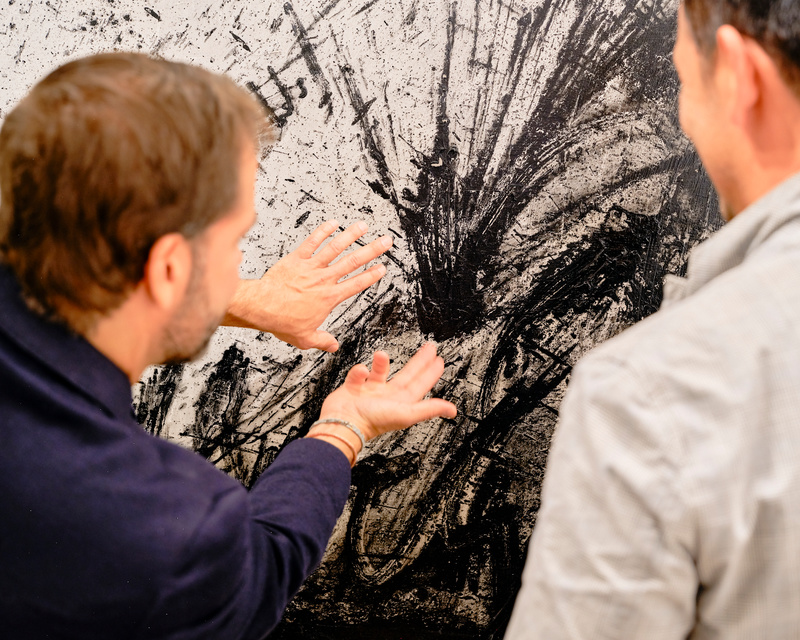 Two men admire a black and white abstract painting