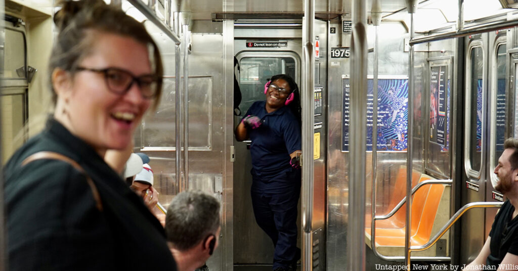 a subway conductor waves inside a subway car