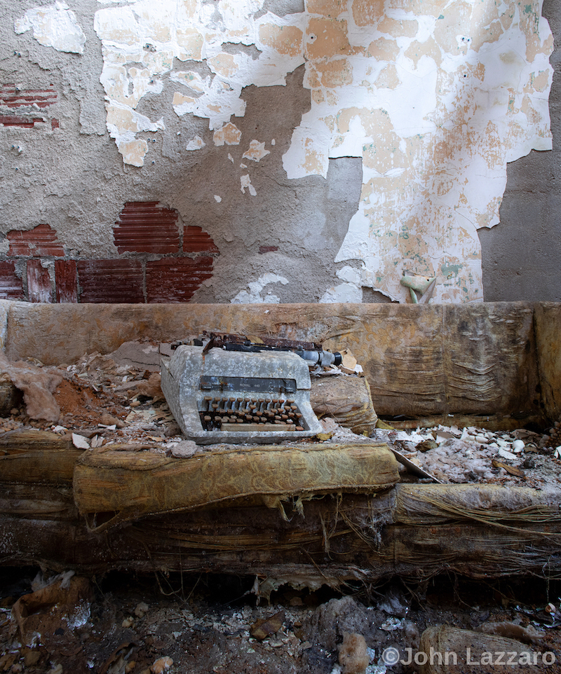 Old typewriter against a wall with peeling paint